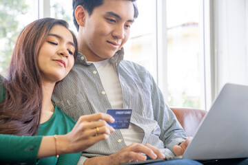The couple is using a credit card to purchase goods online at home