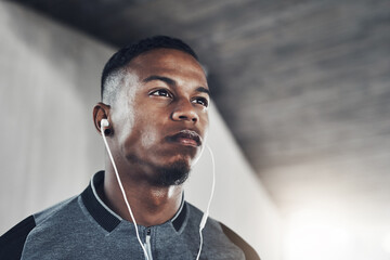 Exercise, earphones and man with thinking for fitness, training planning and workout podcast. Male person, serious and idea with headphones for streaming, music and cardio for wellness in low angle