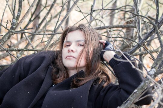 Tranquil woman resting in nature, peacefully lying on branches in forest.