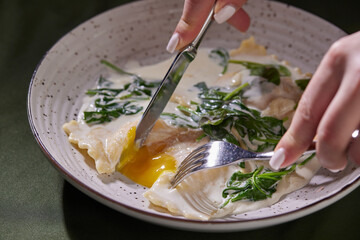 ravioli on a dark plate in hands, top view, vertical photo