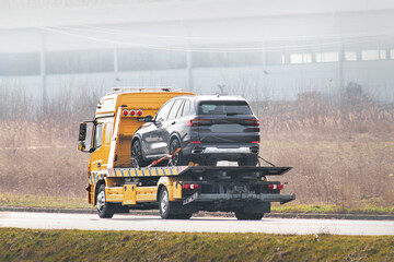 Flatbed towing truck with a car on the road. Roadside assistance. Car service transportation...