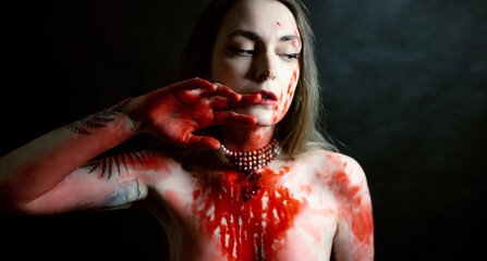 Portrait of young woman with red paint on her chest on dark background. - 791437051