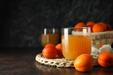 Rolgordijnen A glass of fresh apricot juice on a dark background © Atlas