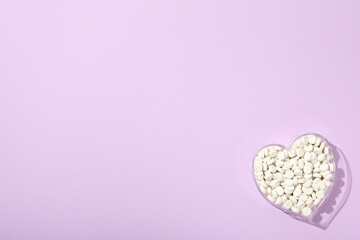 Hormonal pills for the heart, on a purple background. - obrazy, fototapety, plakaty