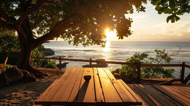 Fototapeta A terrace with a wooden table overlooking a beach landscape bathed in either sunset or sunrise light, featuring a silhouette of a tropical tree against a seascape, perfect for a summer vacation