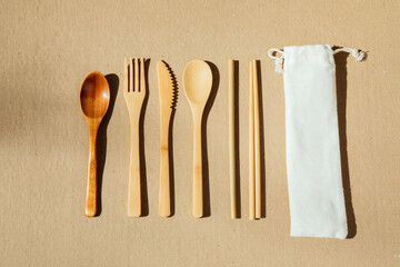 A set wooden cutlery on a brown cardboard background. Eco friendly, zero waste concept. Top view
