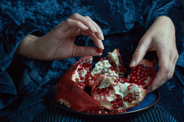 Female hand holds a pomegranate seed. Close-up shot with rich colors and textures. Healthy eating...
