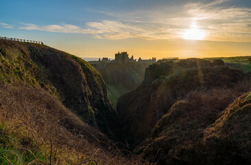 Sun rising over the gorge leading to Dunnottar Castle near Stonehaven in Aberdeenshire, Scotland