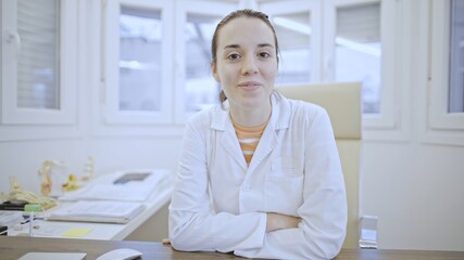 Young Caucasian female doctor seated confidently at desk.