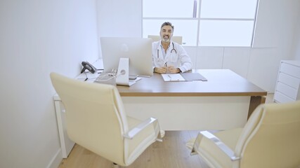 Caucasian Doctor waiting in office with computer setup.