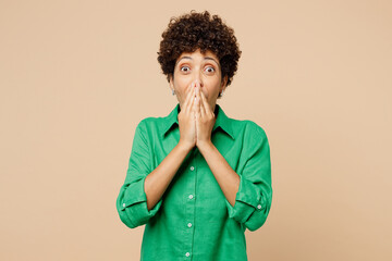 Young surprised shocked woman of African American ethnicity wears green shirt casual clothes cover...