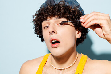 Close up young happy gay Latin man wear mesh tank top hat clothes do make up paint lashes use...
