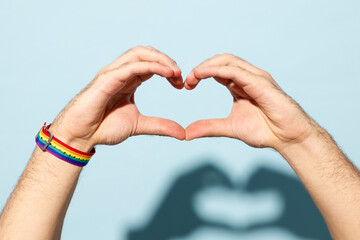 Close up cropped gay male hold hand in heart-shape gesture show heart sign isolated on pastel plain...