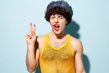 Young cool gay Latin man wear mesh tank top hat clothes with red lipstick make up show v-sign look...
