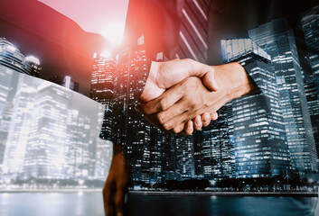 Double exposure image of business people handshake on city office building in background show...