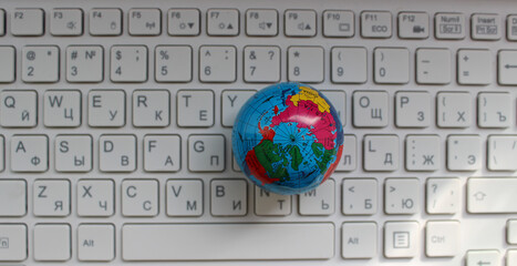 Small Globe On White Keyboard With Latin And Cyrillic Characters Top View
