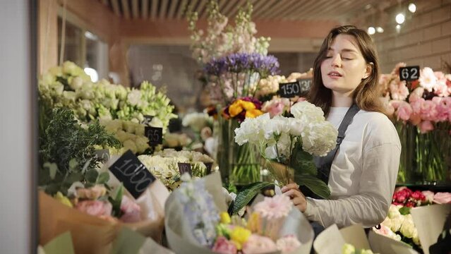 Busy florist make bouquet in flower shop workplace. Small business owner work floral composition in plant store. Young retailer woman preparing an order in floristic boutique. Flowers refrigerator