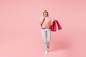 Full body elderly happy surprised fun young woman wearing casual clothes hold paper package bags after shopping scream isolated on plain light pink background studio Black Friday sale buy day concept