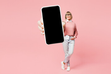 Full body elderly woman 50s years old wear sweater shirt casual clothes glasses with hold use mobile cell phone blank screen workspace area isolated on plain pink background studio. Lifestyle concept.