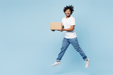 Full body young happy Indian man wear white t-shirt casual clothes hold blank cardboard box look camera jump high isolated on plain pastel light blue cyan background studio portrait Lifestyle concept