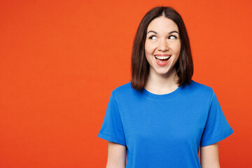 Young surprised shocked excited fun exultant woman she wear blue t-shirt casual clothes look aside on area mockup isolated on plain red orange color wall background studio portrait. Lifestyle concept.