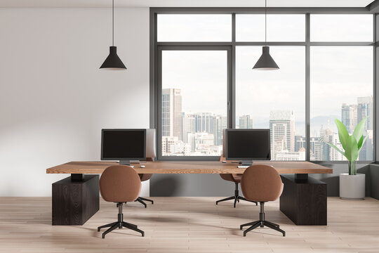 Modern coworking interior with pc computers on desks in row, panoramic window