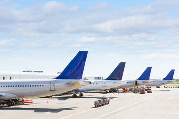 Fototapeta na wymiar Tails of some airplanes at airport during boarding operations. They are four planes on a sunny day, with a blue sky. Travel and transportation concepts.