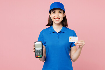 Delivery girl employee woman wears blue cap t-shirt uniform workwear work as dealer courier hold bank payment terminal process acquire credit card isolated on plain pink background. Service concept.