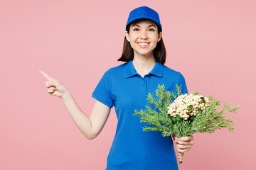 Professional delivery girl employee woman wear blue cap t-shirt uniform workwear work as dealer courier hold bouquet of flowers point finger aside isolated on plain pink background. Service concept. - 791453821