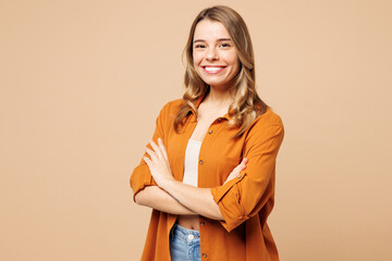 Side view young smiling Caucasian woman she wear orange shirt casual clothes hold hands crossed folded look camera isolated on plain pastel light beige background studio portrait. Lifestyle concept. - 791453855