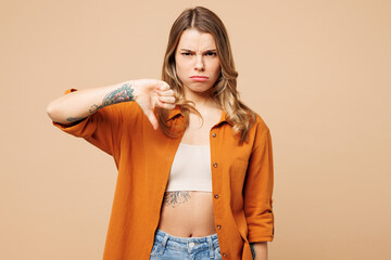 Young displeased dissatisfied sad Caucasian woman wear orange shirt casual clothes showing thumb down dislike gesture isolated on plain pastel light beige background studio portrait Lifestyle concept - 791453897