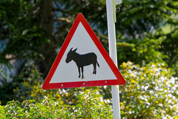 Triangle shaped warning sign caution donkey crossing at Swiss village of Kehrsiten on a sunny spring day. Photo taken April 11th, 2024, Kehrsiten, Switzerland.