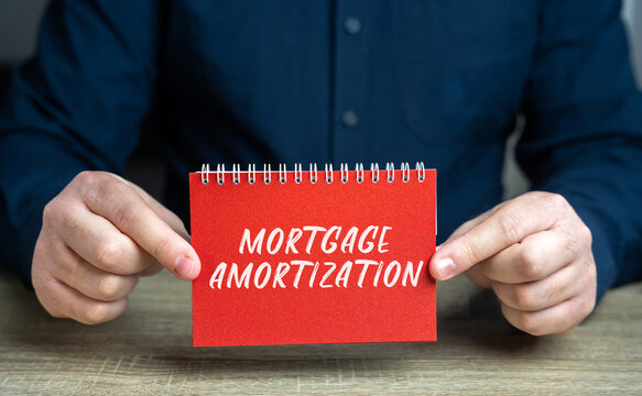 Mortgage amortization concept. Process of paying off a mortgage loan through regular payments over time. Real estate and loan. Notepad in the hands of man