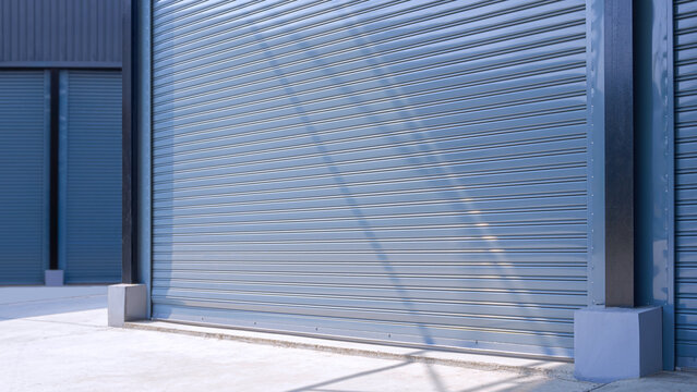 Automatic gray roller shutter entrance door of industrial warehouse building in factory area, perspective side view