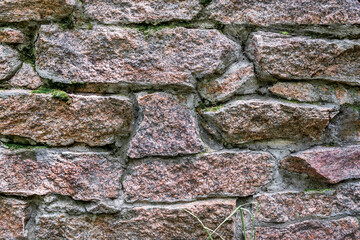 Granite masonry covered with moss. The unique pattern and texture of old stone.