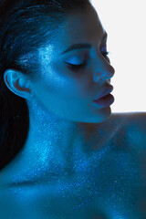 Woman beauty profile with shimmering skin is highlighted by a soothing blue glow, makeup