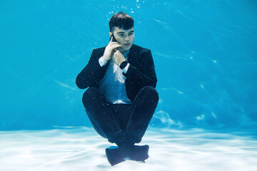 Crazy businessman talking on the phone while submerged underwater
