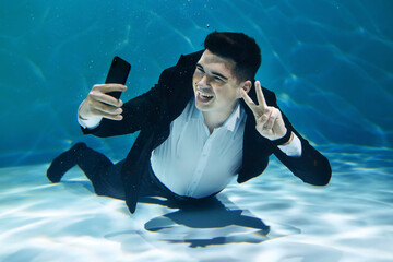 Crazy businessman chatting on smartphone while submerged underwater