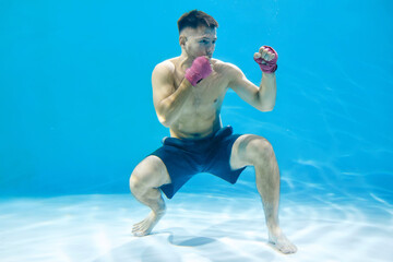 Artistic concept. Athletic man boxing underwater