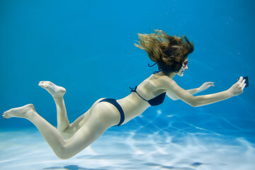 A young woman in a swimsuit takes a photo while underwater. Creative concept