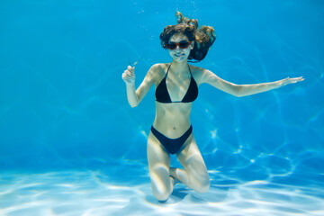 A young woman in a swimsuit is submerged under water. Creative concept