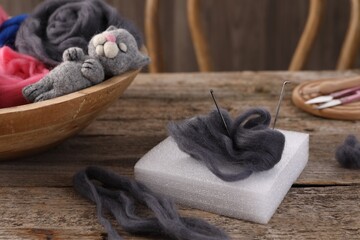 Felting tools, wool and toy cat on wooden table