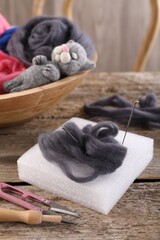 Obraz na płótnie Canvas Felting tools, wool and toy cat on wooden table