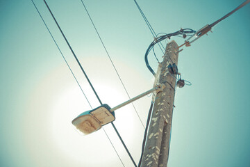 Low angle view of utility pole with electrical wires and a streetlight against a clear sky