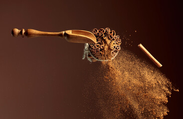 Cinnamon powder is poured out of the wooden spoon.