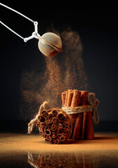 Cinnamon powder is poured out of the strainer. - obrazy, fototapety, plakaty