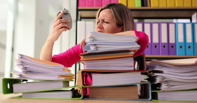 Tired office worker struggling to meet deadline and looking at alarm clock