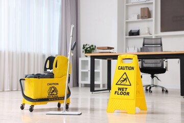 Cleaning service. Mop, bucket and wet floor sign in office