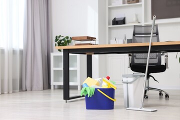 Cleaning service. Mop and bucket with supplies in office, space for text