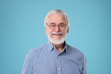 Portrait of stylish grandpa with glasses on light blue background